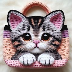 a crocheted purse with a cat face on the front and sides, sitting on a white surface