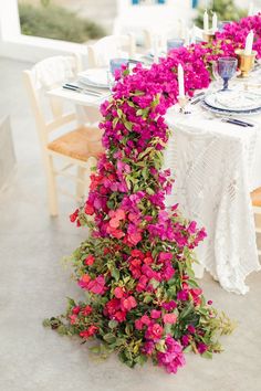 the table is set with pink flowers on it and white linens are draped over