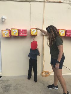 a woman and child are playing with nintendo wii game controllers in front of a wall