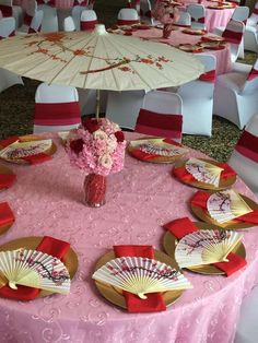 the table is set with pink and gold plates, napkins, and an umbrella