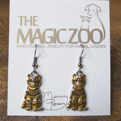 "There's nothing quite like an orange tabby cat! These hand painted kitty earrings are 1\" tall and about ½ wide. The earrings come on stainless steel wires and are ready to show off. Lightweight and comfortable, they are beautifully crafted in fine pewter before being painted by hand. The original model for The Magic Zoo's unique enamel jewelry was created by artist Merry Rosenfield in her home studio. Merry sculpts each design in polymer clay. She uses only her hands and sometimes an occasiona Gold Metal Cat Design Earrings, Gold Metal Earrings With Cat Design, Nickel-free Novelty Gold Earrings, Novelty Gold Nickel-free Earrings, Nickel-free Gold Novelty Earrings, Ginger Tabby Cat, Parrot Necklace, Ginger Tabby, Kitty Necklace