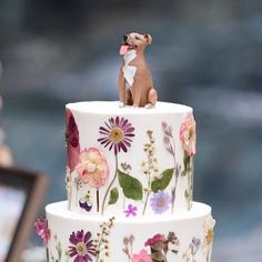 a three tiered cake decorated with flowers and a dog figurine