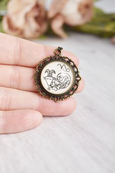 a person is holding a brooch with a drawing on it