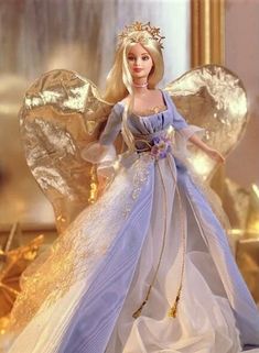 a barbie doll dressed in blue and white with gold wings on her head, standing next to a mirror