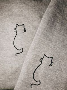 two sweatshirts with cats drawn on them