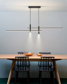 a wooden table with two plates on it and three lights hanging from the ceiling above