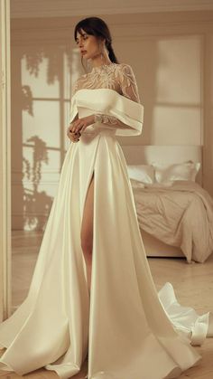 a woman in a white wedding dress standing on the floor with her leg slit open