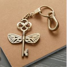 a golden key with a dragonfly on it is sitting on a piece of paper