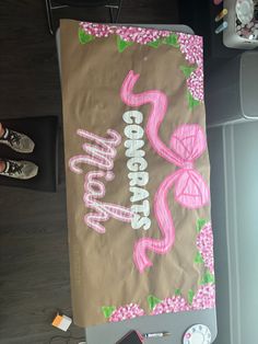 a brown paper bag with pink writing and flowers on it, sitting on top of a table