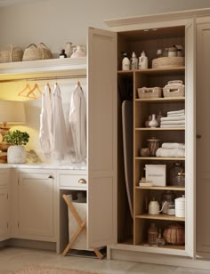 an open closet with clothes hanging on the wall and other items sitting on shelves in front of it