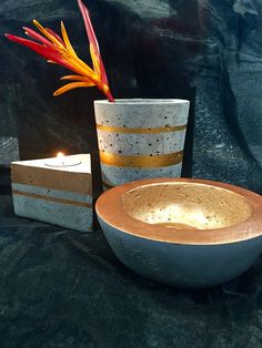 two vases and a candle are sitting on a black surface with a gold stripe design