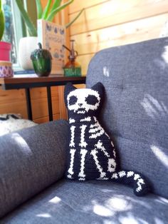 a knitted toy sitting on top of a couch next to a potted plant