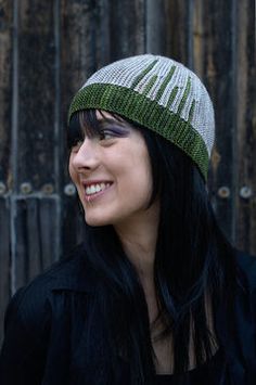 a woman with long black hair wearing a green and white knitted beanie hat