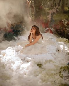 a woman sitting on top of a pile of white fluffy material with steam coming out of her mouth