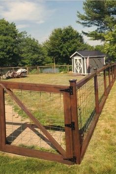 a wooden fence with wire around it and a shed in the back ground behind it