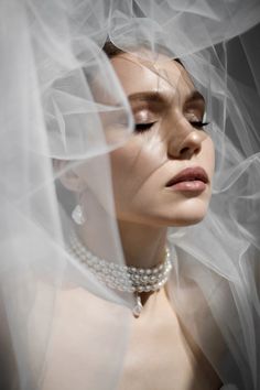 a woman wearing a veil and pearls necklace