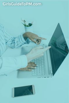 two people sitting at a table using laptops and pointing their fingers to each other