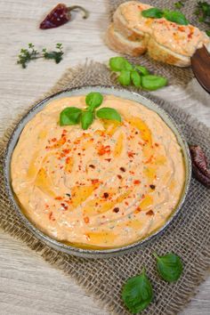 an image of a bowl of dip with bread and basil on the side for garnish