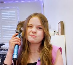 a girl is blow drying her hair with an electric blow dryer in front of her