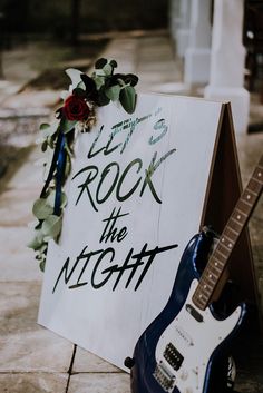 a sign that says rock the night next to a guitar