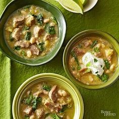 three bowls of soup with meat, beans and spinach on a green tablecloth