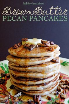 a stack of pancakes with walnuts and butter sitting on top of a floral plate