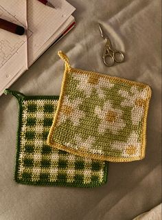 two crocheted bags sitting on top of a bed next to a pair of scissors