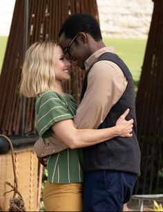 a man and woman embracing each other in front of a wooden structure