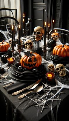 a table topped with black plates covered in skulls and pumpkins next to lit candles