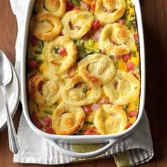 a casserole dish with ham, cheese and vegetables in it on a wooden table