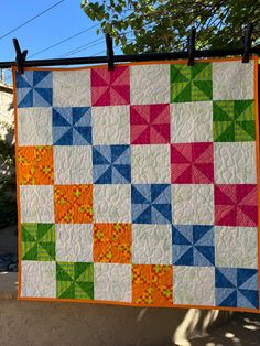 a colorful quilt hanging on a clothes line