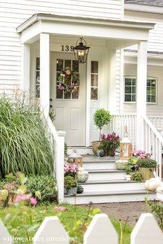 the front porch is decorated with flowers and potted plants