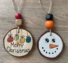 two christmas ornaments hanging from wood slices on a table