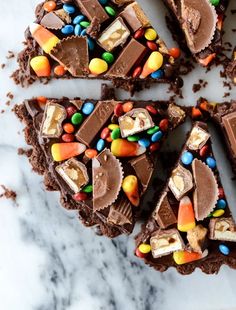 several pieces of chocolate cake with candy and candies on top, sitting on a marble surface