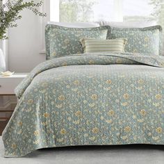 a bed in a bedroom with blue and yellow flowers on the comforter, pillows and pillow cases