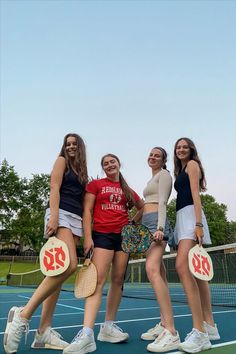 four girls standing on a tennis court with their racquets