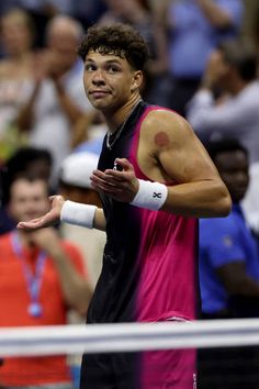 a male tennis player holding a racket in his hand and looking at the crowd