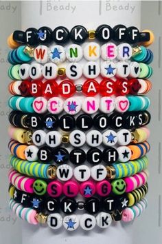 a stack of bracelets with words written in different colors and sizes on them, all stacked together