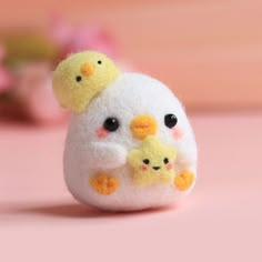 a small stuffed animal with two chicks on it's back sitting on a pink surface