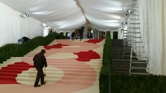 a man is walking down the stairs in front of some white and red carpeted steps