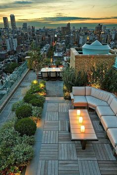 an outdoor seating area with candles lit on the tables and benches in front of cityscape