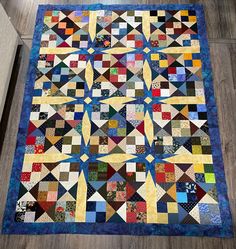 a quilt is laying on the floor with it's center piece in blue and yellow