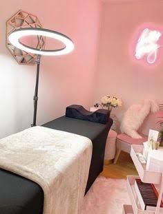 a room with pink walls and black bed in the corner, white fur rugs on the floor