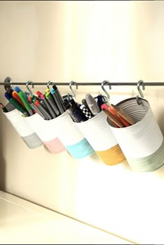 several cups with pens and pencils hanging on a rack