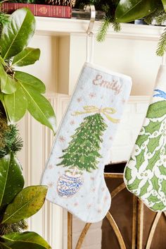 two christmas stockings hanging from a mantel decorated with evergreens and holly tree ornaments