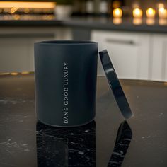 a black coffee mug sitting on top of a table next to a candle light holder