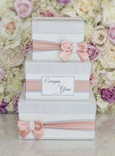 three tiered wedding cake with pink and white flowers in the background, on top of each other