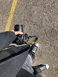 a person holding a camera in their hand on the ground next to a yellow line