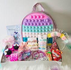 a pink backpack filled with candy, candies and other items sitting on top of a white furnishing