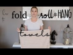 a woman holding up a towel with the words fold and hang on it